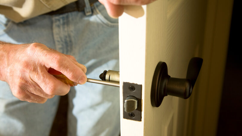 man checking door lock screws